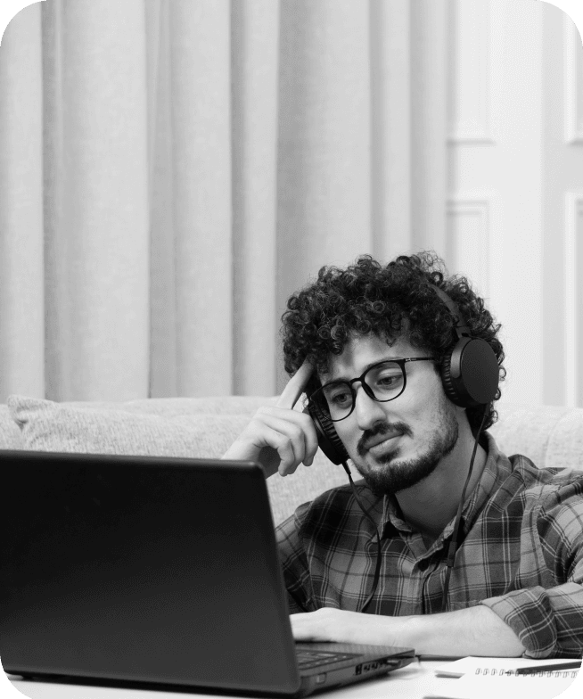 Student with headphones thinking at a laptop
